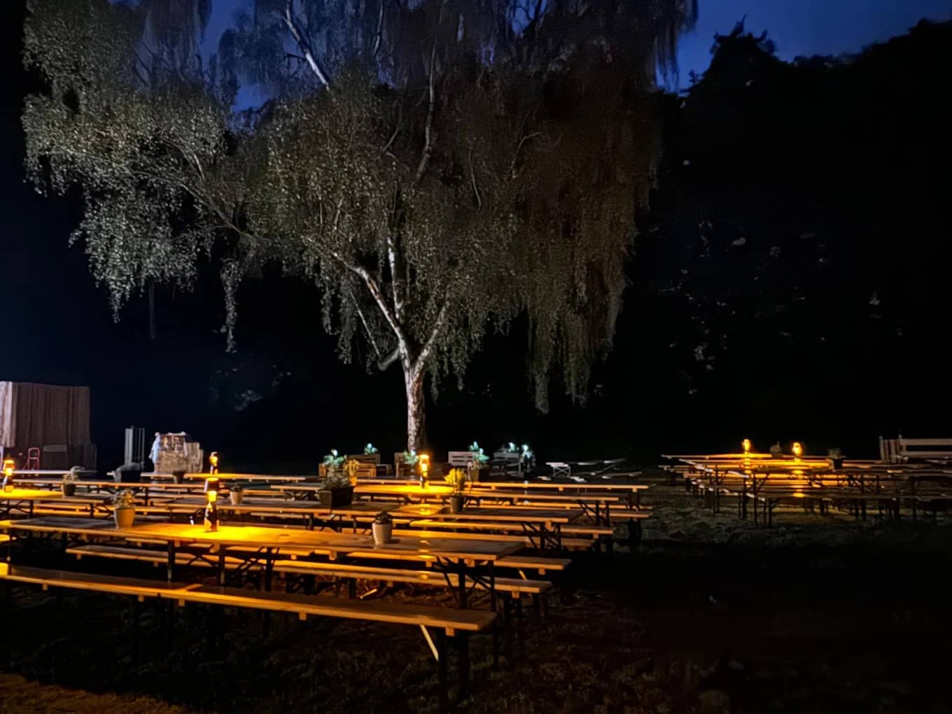 Beleuchtete Tische im Biergarten Thomas am Abend